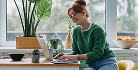 Woman wearing glasses looking happy while at laptop