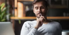 Happy guy holding credit card and looking at computer screen